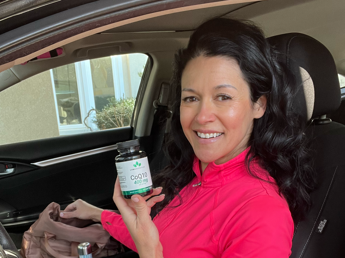 Smiling woman holding Luma Nutrition CoQ10